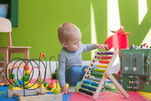 Toddler boy plays educational games in playroom.