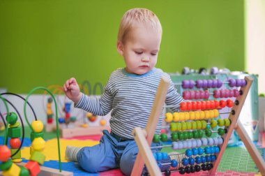 Toddler boy plays educational games in playroom.