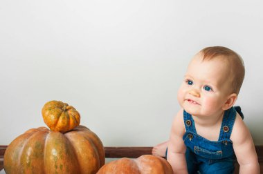 Kot pantolon ve balkabağı giymiş yakışıklı bir bebek. Çocukların tamamlayıcı beslenmesi, yeni yürümeye başlayan ilk sonbahar, Cadılar Bayramı, gıda alerjileri..