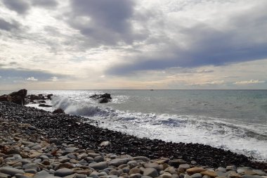 Bir çakıl taşı plajında dalgalar ve Liguria 'daki Diano Marina' da deniz manzarası, İtalya 'daki seyahat ve manzaralar.