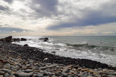 Bir çakıl taşı plajında dalgalar ve Liguria 'daki Diano Marina' da deniz manzarası, İtalya 'daki seyahat ve manzaralar.