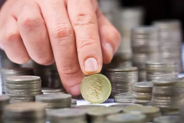 Închiderea stivă de monede de lire sterline britanice cu o mână de sex masculin — Fotografie, imagine de stoc