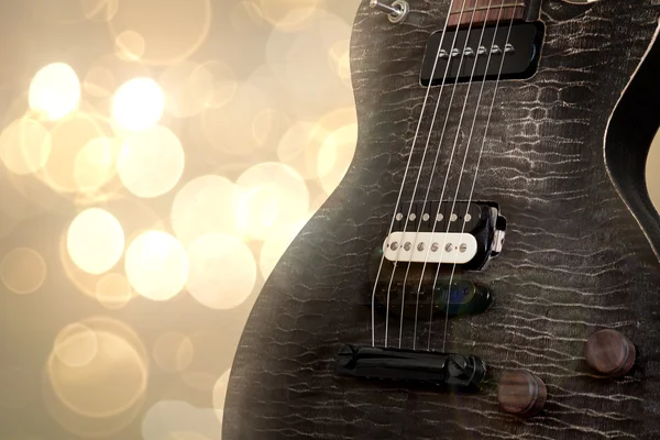 Black electric guitar over a bokeh background — Stock Photo, Image