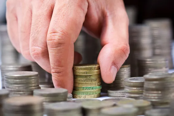 Fechar a pilha de moedas de libra britânicas com uma mão masculina — Fotografia de Stock