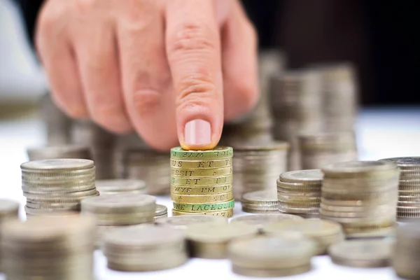 Closeup of stack of british pound coins with a male hand — Stock Photo, Image