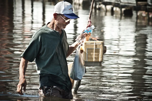 Old man with meal boxes in the middle of the flood — Stock Photo, Image