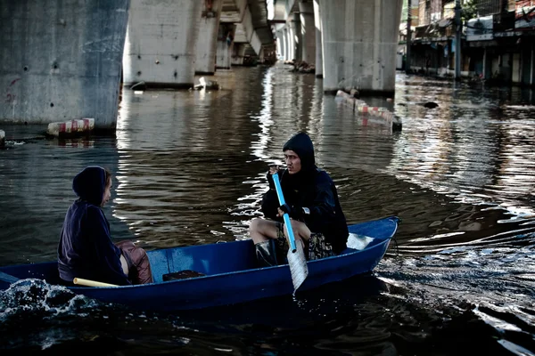 A couple sail a boat ion a road flooded with water — Stock Photo, Image