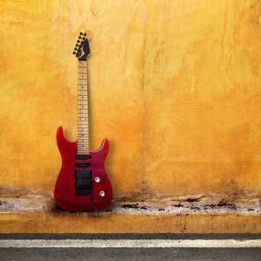 Sarı bir kin duvarda kırmızı eski gitar
