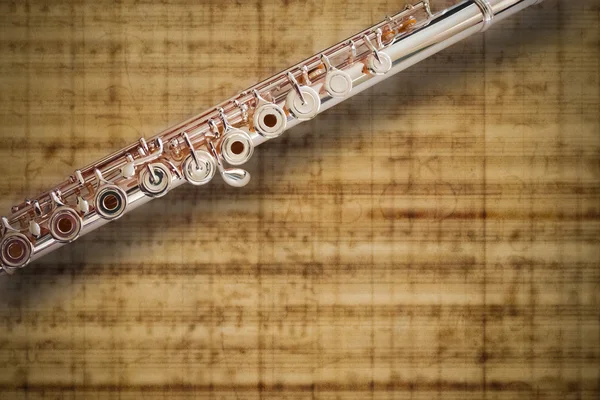 A concert flute on an abstract music score background — Stock Photo, Image