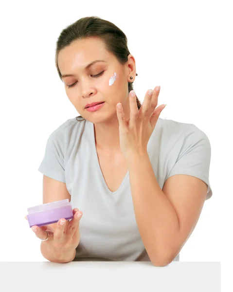 Isolated Middle Age Asian Woman apllies cream on her face. — Stock Photo, Image