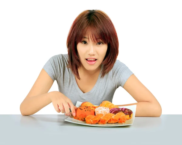 Isolated young asian woman with a donuts on the table — Stock Photo, Image