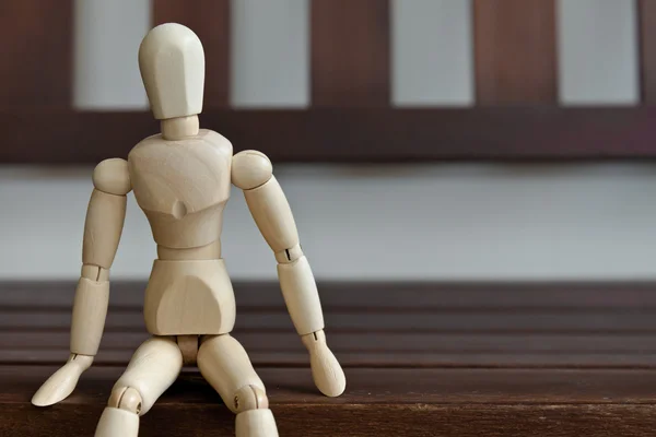 Un maniquí de madera espera en un banco de madera — Foto de Stock