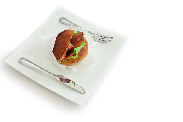 En smörgås med kniv och gaffel på en vit platta — Stockfoto