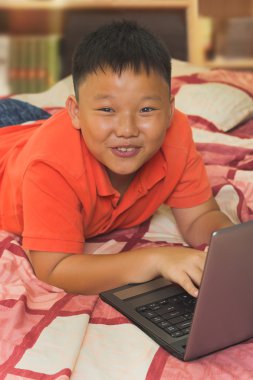 bir dizüstü bilgisayar üzerinde çalışan Asyalı bir çocuk