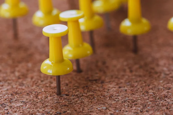 Gele plastic pinnen vorm aan een kurk boord — Stockfoto