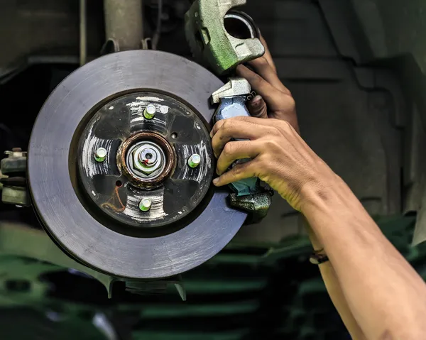 Les mains d'un mécanicien installent une garniture de frein sur un frein à disque de wagon — Photo