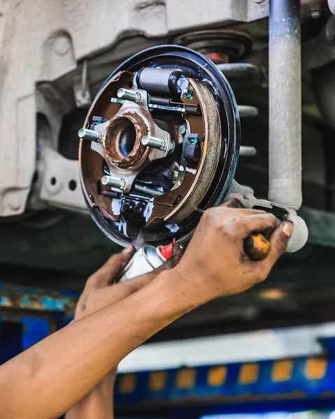 Hands of a mechanic adjusting a car drum brake — Stock Photo, Image