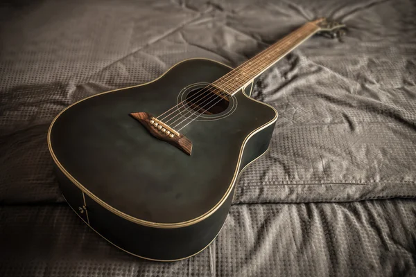 Velho violão empoeirado corte acústico na cama em um quarto deslumbrado — Fotografia de Stock