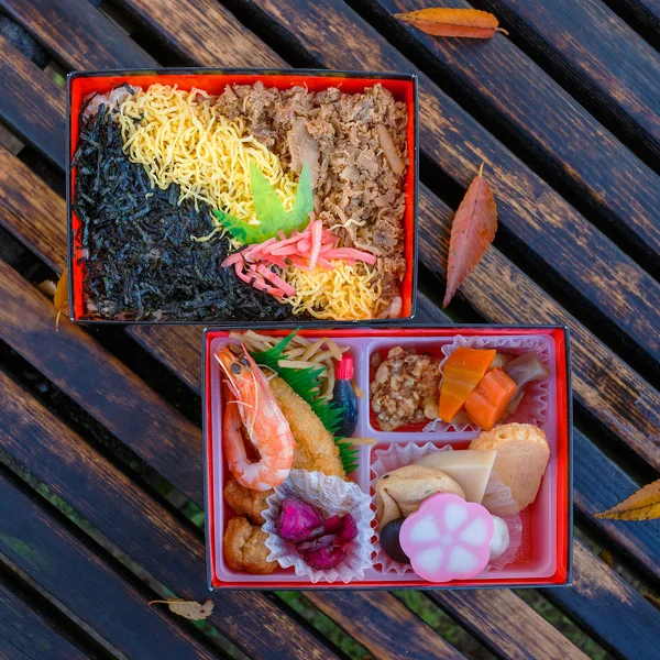 Japanisches Essen (Bento) in Papierschachteln auf einer Holzbank — Stockfoto