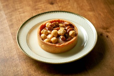 Kısa hamurlu karamelli fındıklı tart. Beyaz tabakta iştah açıcı pasta.