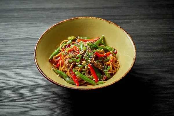 Asian noodles with beef, vegetables, sesame seeds and teriyaki sauce. Street food - noodles wok