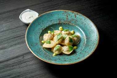 Ahşap bir arka planda mavi bir tabakta beyaz soslu Çin hamur tatlısı.