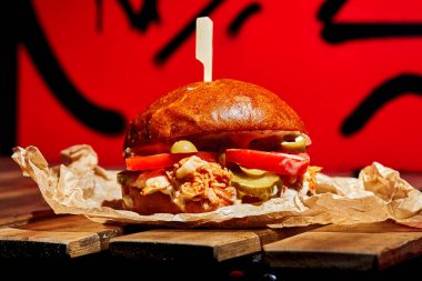 Domates ve peynirli sulu sığır etli burger, parşömen üzerinde sarı sos..