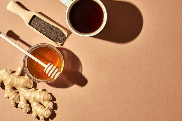 Minimalistic poster - composition with tea, lemon, honey and ginger on a brown background. Healing tea for colds.