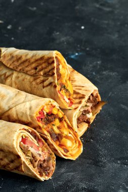 Shawarma sandviçi et ve sebzelerle ikiye bölünmüş. Siyah arka planda Pita ekmeği içinde Shawarma. Yaklaş, seçici odaklanma