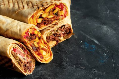 Shawarma sandviçi et ve sebzelerle ikiye bölünmüş. Siyah arka planda Pita ekmeği içinde Shawarma. Yaklaş, seçici odaklanma