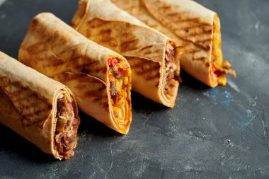 Shawarma sandviçi et ve sebzelerle ikiye bölünmüş. Siyah arka planda Pita ekmeği içinde Shawarma. Yaklaş, seçici odaklanma