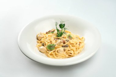 Peynir soslu makarna ve beyaz masa örtüsü üzerinde beyaz tabakta tavuk köftesi.