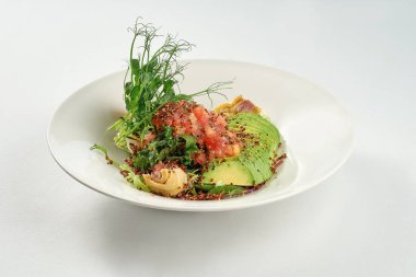 Enginarlı salata, domates, kinoa ve beyaz tabakta avokado. Süper yemek.