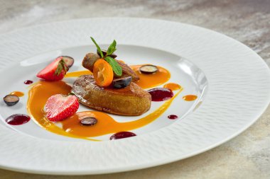 Beyaz tabakta beyaz bir tabakta çilek soslu kızarmış kaz ciğeri.