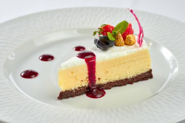 Beyaz tabakta soslu peynirli kek.