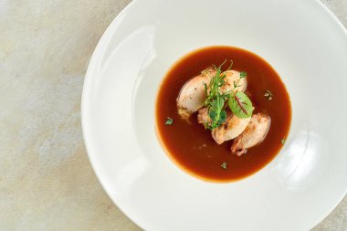 Beyaz bir masa örtüsü üzerinde beyaz bir tabakta soslu mürekkep balığı.