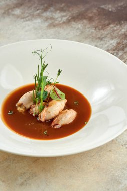 Beyaz bir masa örtüsü üzerinde beyaz bir tabakta soslu mürekkep balığı.