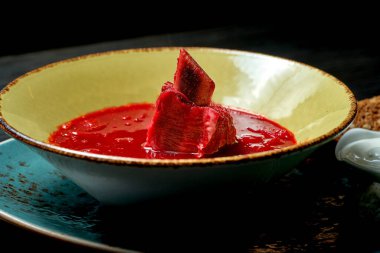 Kaburga, pastırma ve soğanlı Ukrayna Borsch 'u koyu arkaplanda sarı bir tabakta