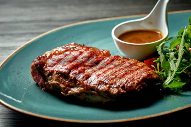 Salatalı biftek ve mavi tabakta bal sosu. Ahşap arkaplan