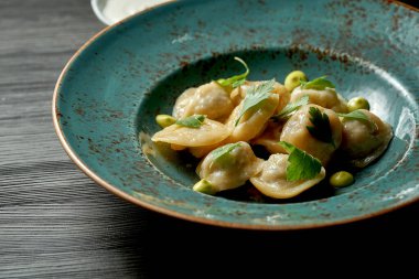 Ahşap bir arka planda mavi bir tabakta beyaz soslu Çin hamur tatlısı.