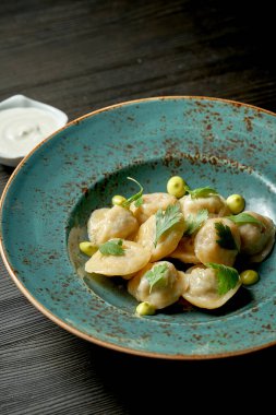 Ahşap bir arka planda mavi bir tabakta beyaz soslu Çin hamur tatlısı.