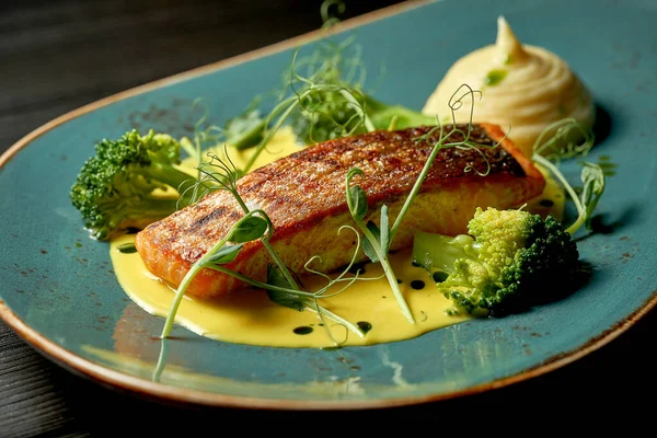Sarı soslu somon bifteği, sebze püresi ve brokoli. Ahşap arkaplan