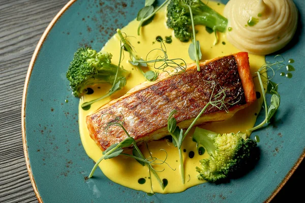 Sarı soslu somon bifteği, sebze püresi ve brokoli. Ahşap arkaplan