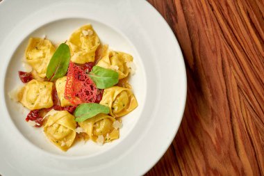 Farklı soslu Ravioli ve ahşap arka planda beyaz bir tabakta parmesan.