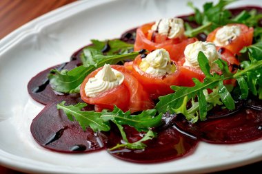 Krem peynirli az tuzlu somon, ahşap arka planda pancar carpaccio ile servis edilir.