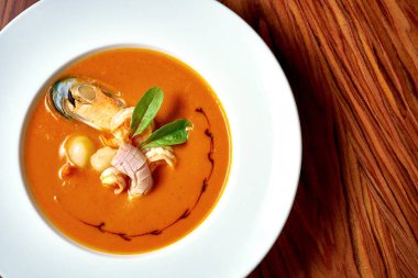 Karidesli Asya çorbası ve ahşap arka planda beyaz bir tabakta tavuk.