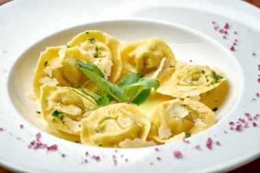 Farklı soslu Ravioli ve ahşap arka planda beyaz bir tabakta parmesan.