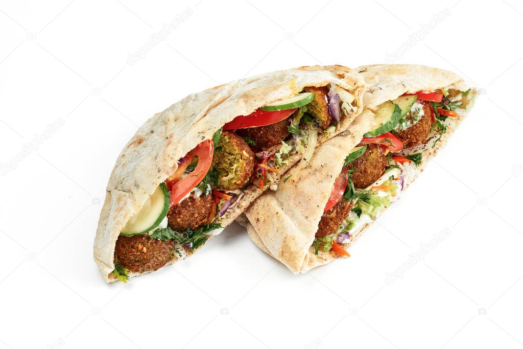 Pita with falafel, fresh vegetables and white sauce on a white plate. Photo for the menu. Isolated