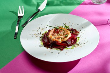 Baked salmon with beets and spices in a white plate. Colored backgrounds. Hard light. selective focus