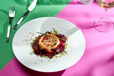 Baked salmon with beets and spices in a white plate. Colored backgrounds. Hard light. selective focus